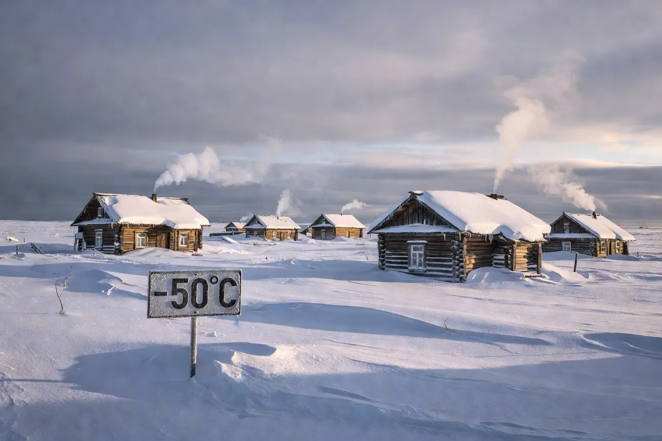 Oymyakon en hiver : panneau de température à -50°C devant les maisons enneigées